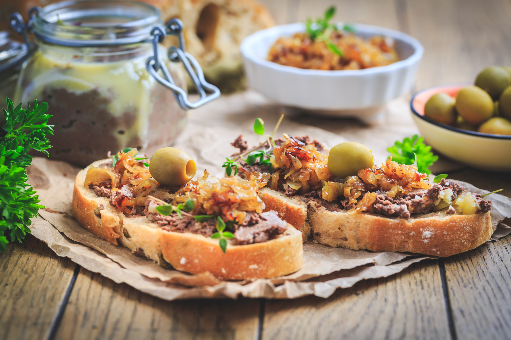 Fresh koji, plant-based pate on ciabatta bread with roasted onions and olives on wooden table