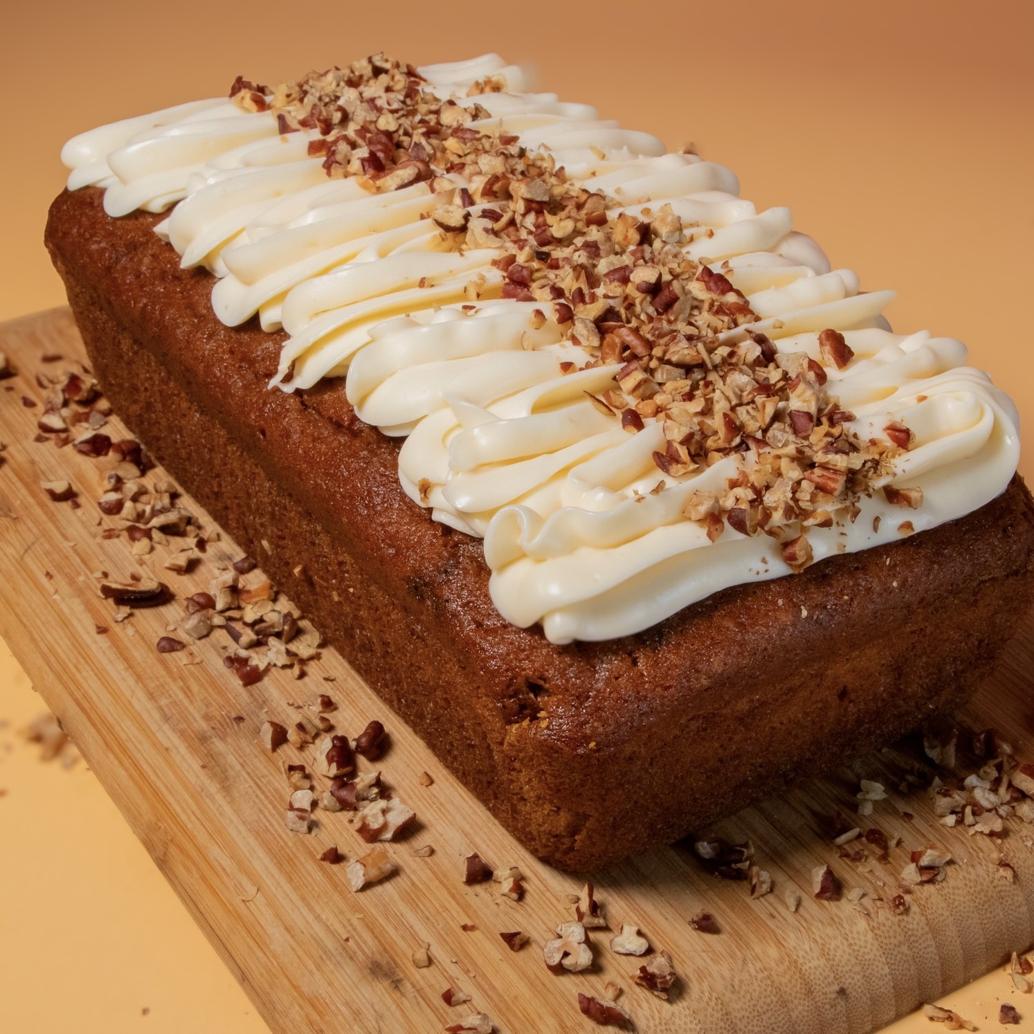 Hummingbird loaf cake topped with cream cheese frosting and chopped pecans.