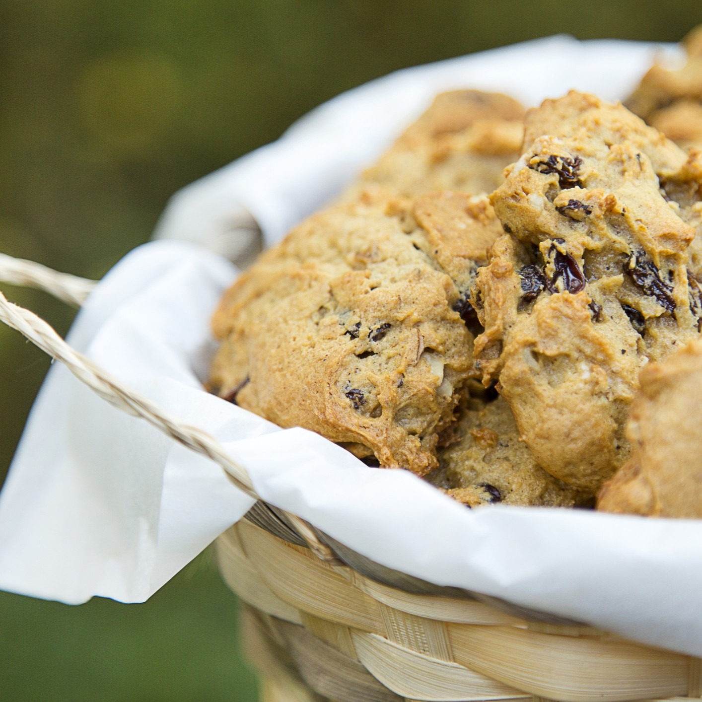 Persimmon cookies with raisins in a wicker basket with white cloth.